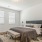 Modern furnished bedroom with a bed and a bench in townhome at The Harris