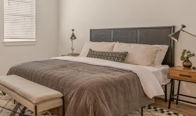 Sleep in style Furnished bedroom with a bed and bench in townhome at The Harris